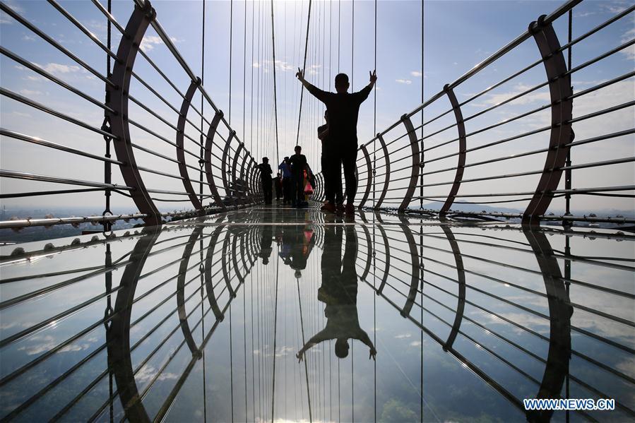 <?php echo strip_tags(addslashes(Tourists walk on a glass bridge at the Huaxi World Adventure Park in Huaxi Village of Jiangyin City, east China's Jiangsu Province, May 4, 2019. The 518-meter-long glass bridge hangs more than 100 meters above ground level at the park. It is made of panes of 35-mm-thick glass. Each glass can hold a maximum weight of 4.7 tonnes. Around 2,600 people can cross the bridge at a time. (Xinhua/Xu Congjun))) ?>