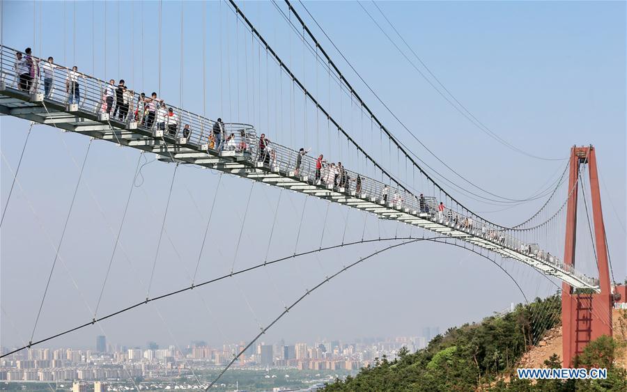 <?php echo strip_tags(addslashes(Tourists walk on a glass bridge at the Huaxi World Adventure Park in Huaxi Village of Jiangyin City, east China's Jiangsu Province, May 4, 2019. The 518-meter-long glass bridge hangs more than 100 meters above ground level at the park. It is made of panes of 35-mm-thick glass. Each glass can hold a maximum weight of 4.7 tonnes. Around 2,600 people can cross the bridge at a time. (Xinhua/Xu Congjun))) ?>