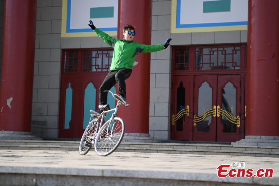 Zhou Changchun, 59, shows off his cycling stunts at a square in Changchun City, Northeast China\'s Jilin Province, May 7, 2019. Zhou is able to perform a number of stunts while riding his bicycle, including standing and lifting dumbbells with both hands. (Photo: China News Service/Zhang Yao)