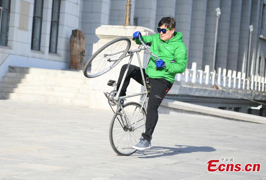 Zhou Changchun, 59, shows off his cycling stunts at a square in Changchun City, Northeast China\'s Jilin Province, May 7, 2019. Zhou is able to perform a number of stunts while riding his bicycle, including standing and lifting dumbbells with both hands. (Photo: China News Service/Zhang Yao)