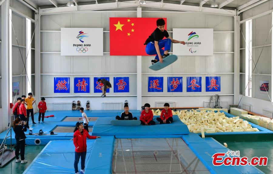 <?php echo strip_tags(addslashes(A student practices snowboarding under the instruction of coach Sun Zhifeng (with blue hat) at the Youth Winter Olympic Sports School, or Xuanhua No. 2 Middle School, in Zhangjiakou, Hebei Province, May 9, 2019. The school established in 2015 is the only of its kind to specialize on training of Winter Olympic sports in China. The school has recruited more than 1,200 students, including 200 trained to be competitive skiers. Located some 200km northwest of Beijing, Zhangjiakou will host snowboarding, freestyle skiing, cross-country skiing, ski jumping, Nordic combined and biathlon competitions during the 2022 Winter Games. (Photo: China News Service/Zhai Yujia))) ?>