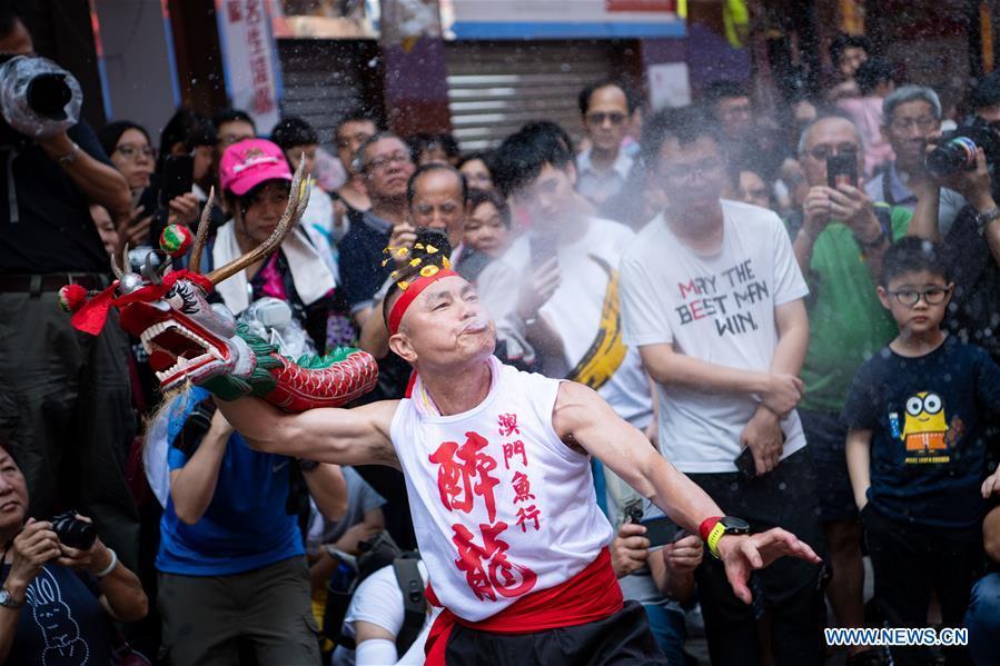 A man performs drunk dragon dance during the Drunken Dragon Festival to celebrate the Buddha\'s birthday in south China\'s Macao, May 12, 2019. Recognized as an item of China\'s national intangible cultural heritage, the Drunken Dragon Festival originates from a Macao legend of a Buddhist monk and a divine dragon who saved people from the plague during the Qing Dynasty. (Xinhua/Cheong Kam Ka)
