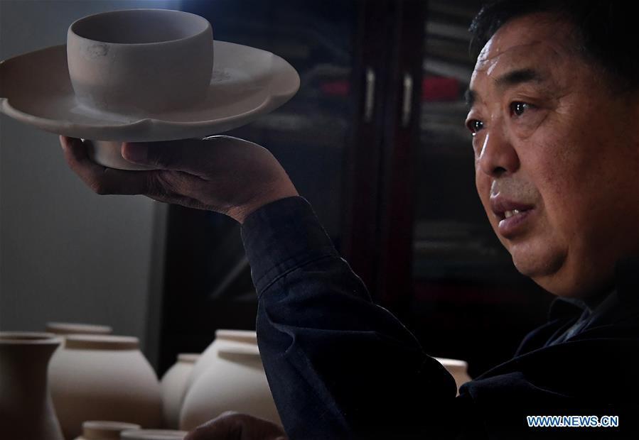 Wang Junzi checks a Ru porcelain work at his studio in Qingliangsi Village, Baofeng County of central China\'s Henan Province, May 8, 2019. Ru porcelain, one of the five famous kinds of porcelains during the Song Dynasty (960-1279) in ancient China, is known for its azure color, light body, filmy grain and gentle textile. Wang Junzi, born in 1960, is a Ru porcelain firing craftsman in Qingliangsi Village of Baofeng County in central China\'s Henan, where the ancient official Ru porcelain kiln in Song Dynasty is located. In order to reproduce the beauty of \