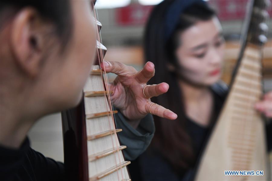 Players Zhang Geping (L) and Zhao Xiaotong practice playing the pipa at Lanzhou traditional orchestra in Lanzhou, northwest China\'s Gansu Province, May 13, 2019. Pipa, a pear-shaped stringed instrument, is one of the traditional Chinese musical instruments. The pipa is played vertically and can be found in solos, ensembles or orchestras. The images of flying apsaras playing the pipa have been seen on murals in Gansu\'s Dunhuang Mogao Grottoes, a 1,600-year-old UNESCO world heritage site located at a cultural and religious crossroads area on the ancient Silk Road in Gansu. Nowadays contemporary dance performances inspired from those images on the murals have been staged times and times again. (Xinhua/Chen Bin)