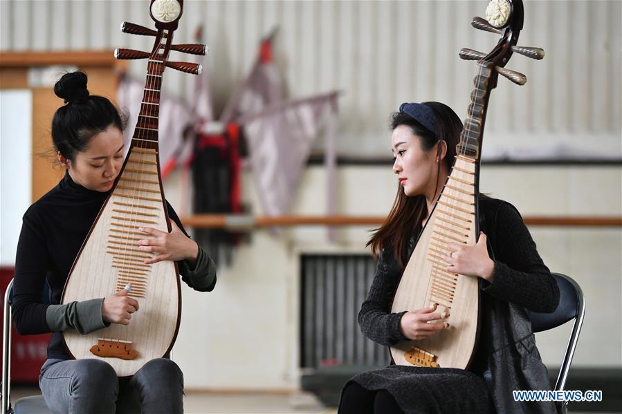 Players Zhang Geping (L) and Zhao Xiaotong practice playing the pipa at Lanzhou traditional orchestra in Lanzhou, northwest China\'s Gansu Province, May 13, 2019. Pipa, a pear-shaped stringed instrument, is one of the traditional Chinese musical instruments. The pipa is played vertically and can be found in solos, ensembles or orchestras. The images of flying apsaras playing the pipa have been seen on murals in Gansu\'s Dunhuang Mogao Grottoes, a 1,600-year-old UNESCO world heritage site located at a cultural and religious crossroads area on the ancient Silk Road in Gansu. Nowadays contemporary dance performances inspired from those images on the murals have been staged times and times again. (Xinhua/Chen Bin)