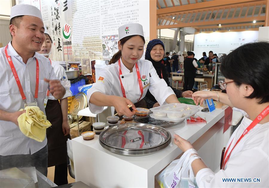 A visitor prepares to taste steamed dumplings with juicy stuffings during the Asian Cuisine Festival at the Olympic Park in Beijing, capital of China, May 16, 2019. The week-long Asian Cuisine Festival, as part of the Conference on Dialogue of Asian Civilizations (CDAC), was held in four cities of Beijing, Hangzhou, Chengdu and Guangzhou. (Xinhua/Li He)