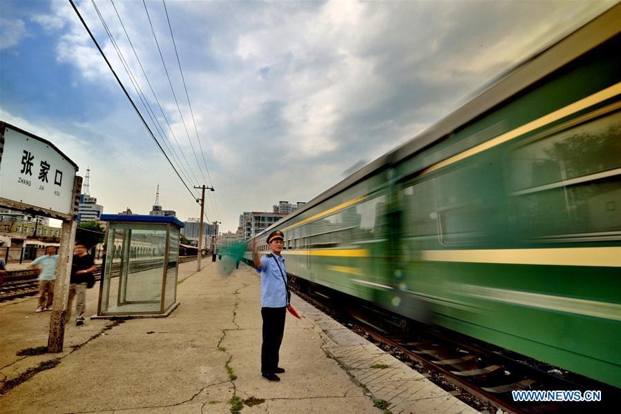 A staff member gestures as the last train runs out of the Zhangjiakou North Railway Station before it was discharged in Zhangjiakou, north China\'s Hebei Province on June 30, 2014. (Xinhua/Yang Shiyao)