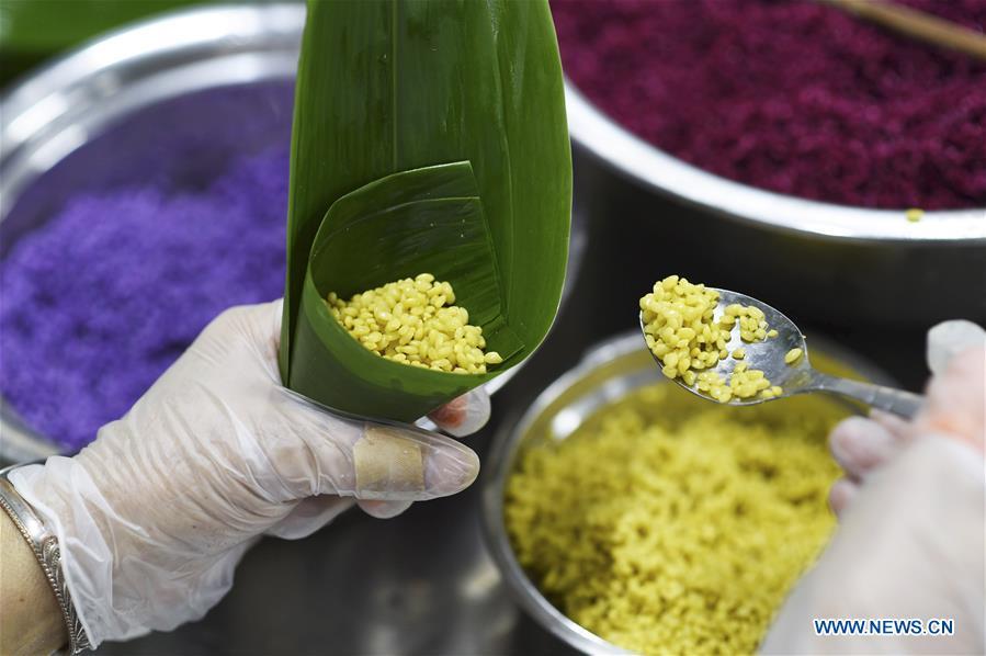 A worker makes colorful Zongzi, pyramid-shaped dumplings made of glutinous rice wrapped in bamboo or reed leaves, at a factory in Taijiang County, southwest China\'s Guizhou Province, June 2, 2019. Different plant juices are used to color the glutinous rice when making the colorful Zongzi. Zongzi is a traditional food for the Dragon Boat Festival, which falls on June 7 this year. (Xinhua/Liu Kaifu)