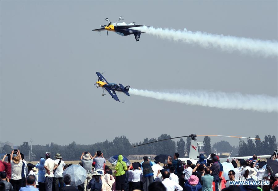 People watch an aerobatic show by enthusiasts in air sports during the opening of the 11th Air Sports Culture and Tourism Festival in Anyang, central China\'s Henan Province, June 3, 2019. The event kicked off Monday in the city of Anyang, attracting air sports fans from home and abroad. (Xinhua/Li An)
