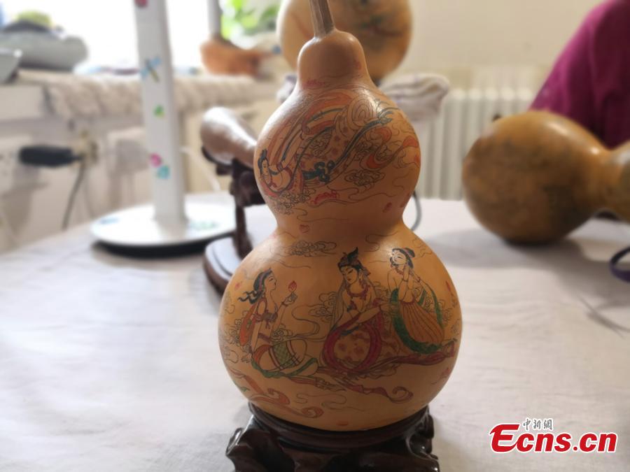Craftswoman Chen Bing shows a gourd she carved in Lanzhou City, Gansu Province in June 2019.  The second generation in her family to make artistic creations on gourds, she carved  characters sometimes just one millimeter in size. (Photo: China News Service/Yang Na)
