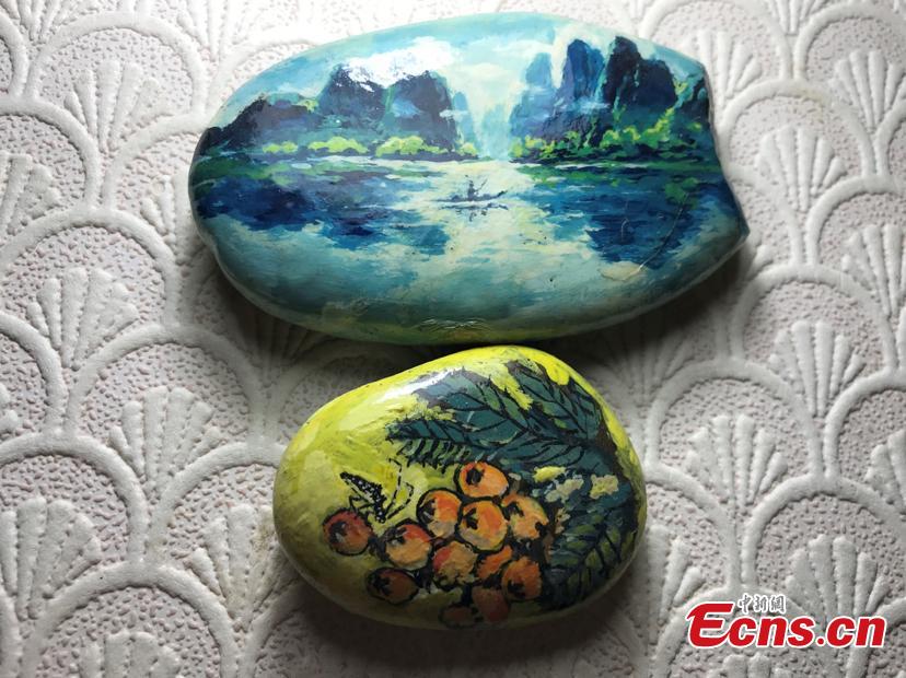 Zhang Yulin shows his paintings on stones.Zhang, 81, from southwest China’s Chongqing municipality, collects stones from the Yangtze River banks and turns them into artworks with paintings.  (Photo: China News Service/Xiao Jiangchuan)