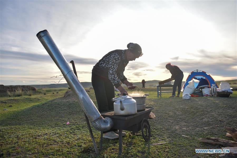 Herdswomen make meals during their trip for summer pasture in Fuhai County of Altay, northwest China\'s Xinjiang Uygur Autonomous Region, on June 5, 2019. As summer comes, herdsmen of Kazak ethnic group here are busy with transferring livestock to summer pastures. (Xinhua/Ding Lei)