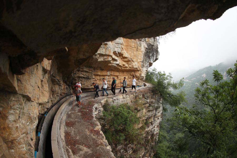 Villagers regularly check the canal carved into cliffs in Gaoliu village, Southwest China\'s Guizhou Province, to make sure it\'s working well. (Photo by Han Xianpu/For chinadaily.com.cn)
