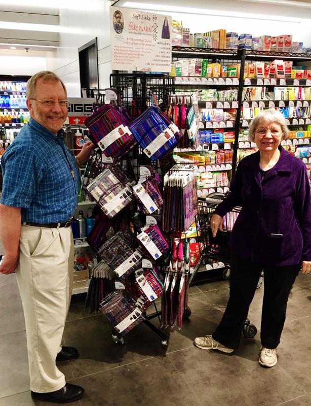 Paul and Dorothy Lacy pose in front of a display of their company\'s embroidery products at a Hong Kong supermarket in 2018.  (Photo provided to chinadaily.com.cn)