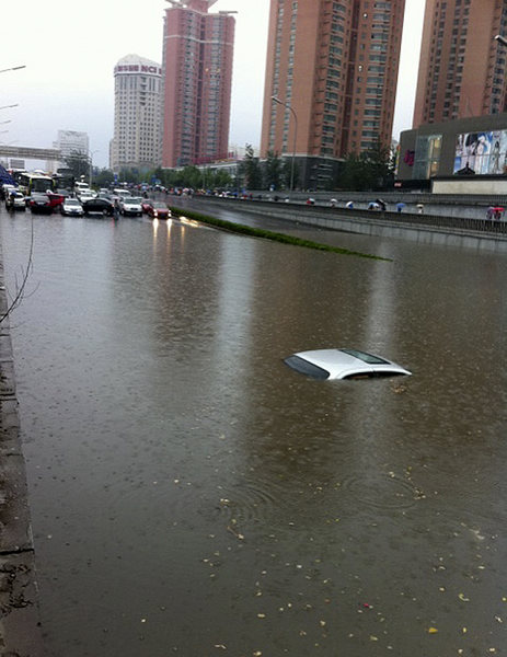 A car is submerged at Lianhuaqiao on the West Third Ring Road on Thursday afternoon. [Photo/Xinhua]