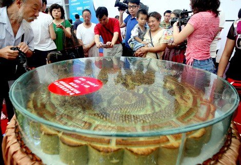 Visitors look at a huge moon cake exhibited in a food fair in Chengdu, Sichuan province, on Sunday.[Photo/China Daily] 