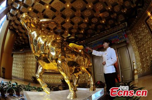 A worker cleans a so-called 400 million yuan statue of a gold bull at a 74-story skyscraper at Huaxi, a village known for its wealth in east China's Jiangsu Province.