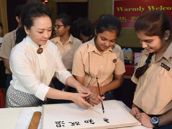 Peng Liyuan, wife of Chinese President Xi Jinping, teaches students to use Chinese writing brush at the Tagore International School in New Delhi, India, Sept. 18, 2014.[Photo: Xinhua]
