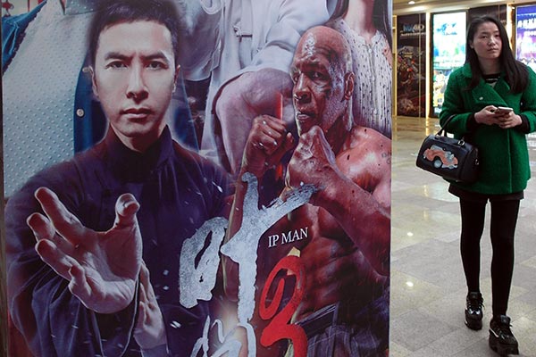 A moviegoer walks past a poster of Ip Man 3 in Yichang, Hubei province. The film's distributor was put under investigation for buying tickets itself to bolster box office numbers. LIU JUNFENG / FOR CHINA DAILY