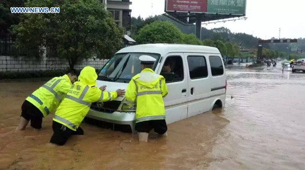 Policemen push a trapped car at the Mingyueshan scenic spot in Yichun, east China's Jiangxi Province, May 6, 2016. Mountain torrents hit the scenic zone and Wentang Town on the foot of the hill at about 11:00 a.m. Friday, causing dozens of people trapped on the mountain. Rescue operation is underway and no casualties have been reported so far. (Xinhua)  