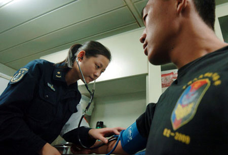 Shao Xiaoqin checks a soldier's blood pressure on board ship. She was one of seven nurses who were the first women to join the escort operations, on the third mission. (Xinhua/ Guo Gang)
