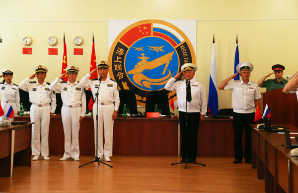 Chinese and Russian navy officers salute their national flags during the closing ceremony of the China-Russia Joint Sea 2013 naval exercises on Thursday in Vladivostok, Russia. [Photo/Xinhua]