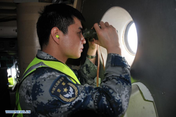 A crew member of Chinese IL-76 aircraft scans the target area to search for missing Malaysia Airlines Flight MH370 above the southern Indian Ocean on March 26, 2014. (Xinhua/Huang Shubo)