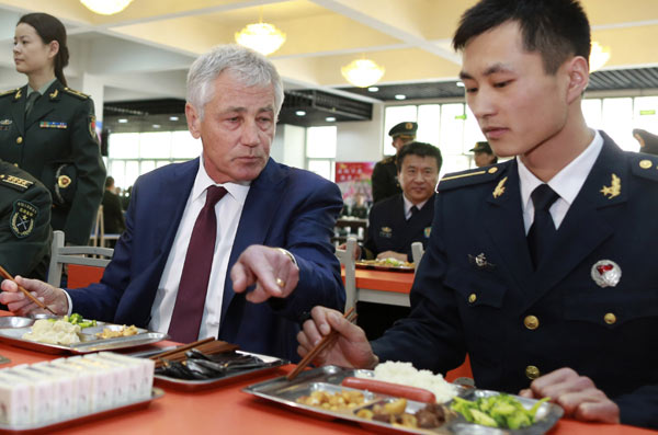 US Defense Secretary Chuck Hagel asks People's Liberation Army soldier Xing Daichun about his sausage and tells him he is young and should eat more as they have lunch together at a canteen in a training academy for noncommissioned officers in the northern suburbs of Beijing on Wednesday. Feng Yongbin / China Daily 