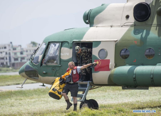 A worker of International Red Cross steps off a helicopter from an army aviation brigade of the Chengdu Military Region of the People's Liberation Army of China in Kathmandu, capital of Nepal, on May 13, 2015. Three Chinese military helicopters of the brigade on Wednesday evacuated 108 people from several areas in Nepal, a day after a fresh 7.5-magnitude earthquake that claimed at least 65 lives and injured over 1,900 people, officials said. (Xinhua/Lui Siu Wai)