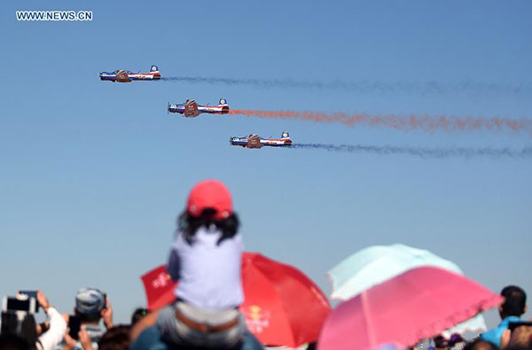 People watch the performance of the Tianzhiyi aerobatic aircrafts from the Aviation University of Air Force at the Dafangshen Airport in Changchun, capital of northeast China's Jilin Province, Sept. 10, 2015.(Photo/Xinhua)