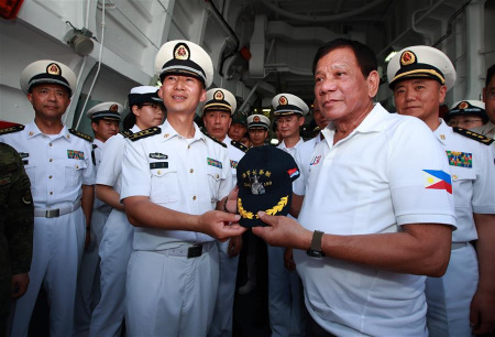 Philippine President Rodrigo Duterte (R, front) receives a hat from Hu Jie (L, front), captain of China's missile destroyer Changchun, in Davao City, the Philippines, May 1, 2017. (Xinhua/Yu Wei)