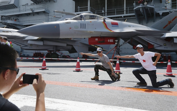 Visitors signal takeoff on the deck of China's first aircraft carrier, the CNS Liaoning, on Sunday, the last day of the open house of the carrier's flotilla in Hong Kong.Roy Liu / China Daily