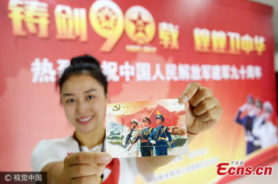A woman shows a miniature sheet as part of a commemorative set of stamps issued to mark the 90th anniversary of the founding of the People��s Liberation Army in Handan City, North China��s Hebei Province, Aug. 1, 2017. (Photo/VCG)