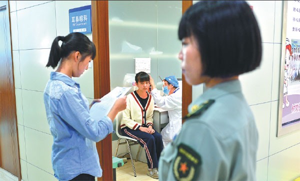 Teenagers have their ears checked during the extensive physical examination process for military recruits in Kunming, Yunnan province, on Monday. Candidates must pass every item on the checklist to be accepted. Gao Wei / For China Daily