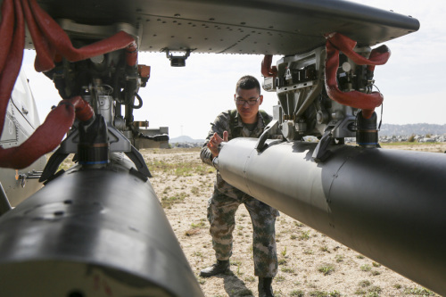 A soldier checks the weaponry on an attack helicopter on Wednesday. (Photo/CHINA DAILY)