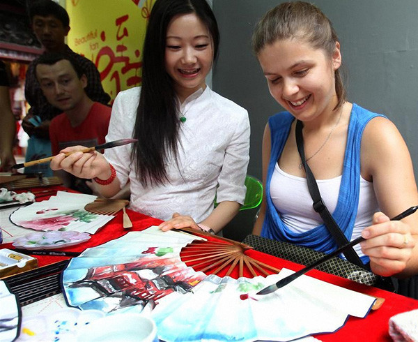 A foreign tourist learns to paint on a traditional Chinese fan in Shanghai in July. (Photo/Xinhua)