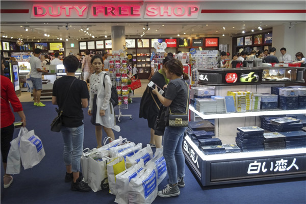 Chinese tourists shop in a duty free store at an airport in Japan. A survey shows Chinese have become the most likely consumers to buy now, pay later.  WANG ZHICHENG/CHINA DAILY