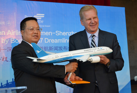 Xiamen Airlines Chairman Che Shanglun (left) gives the Xiamen Airlines Model Plane as a gift to Port of Seattle CEO Ted Fick at the ceremony celebrating the launch of Xiamen-Shenzhen-Seattle service by the airlines at the SeaTac Airport arrival hall Wednesday morning.(Linda Deng/ China Daily) 