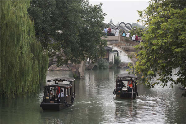 Crisscrossing waterways are now the biggest draw for visitors to Wuzhen, Zhejiang province. Visitors stroll along the banks or hop aboard boats to take in the views. (Photo by Shi Kuihua/For China Daily)