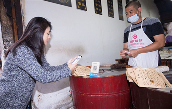 A customer buys sesame seed cakes via smartphone in Wuzhen, Zhejiang province. (Photo/China Daily)