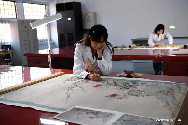 A staff member (front) repairs a painting of the Qing Dynasty at the repair and restoration workshop of the Palace Museum in Beijing, capital of China, Dec. 29, 2016. (Photo/Xinhua)