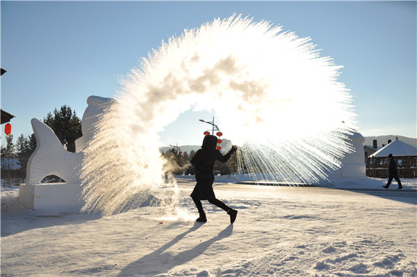 A visitor plays a popular game of splashing hot water, which generates vapor in the cold air. (Photo By Liu Xiangrui / China Daily)