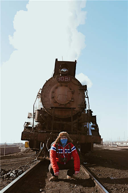Qi Dong poses in front of a train locomotive in Hami, Xinjiang Uygur autonomous region.
