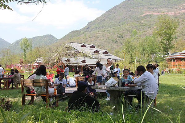 Tourists relax in a meadow in Huaqiao village in Kangxian county, Gansu province.(Photo provided to China Daily)