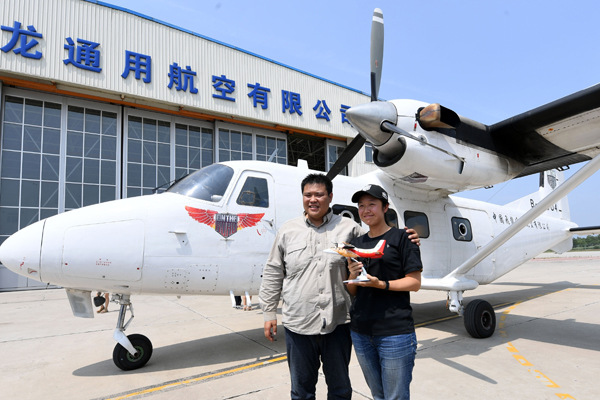 Zhang Xinyu and his wife, Liang Hong, display a model on Wednesday of a Y-12F aircraft, the newest generation of the plane they used to complete their round-the-world trip. China Daily