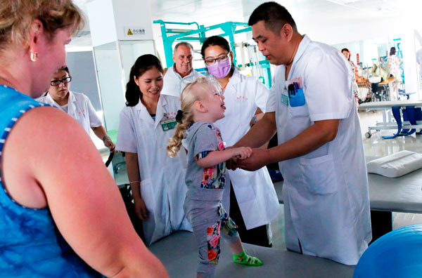 A Russian child with cerebral palsy gets treatment in Sanya Traditional Chinese Medicine Hospital last summer. (Photo provided to China Daily)