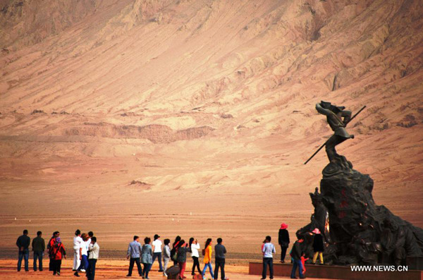 Tourists pose for photos next to a statue of Monkey King, a character of the 16th-century Chinese novel Journey to the West, in the Flaming Mountains Scenic Area in Turpan, Northwest China's Xinjiang Uygur autonomous region, April 6, 2014.(Photo/Xinhua)