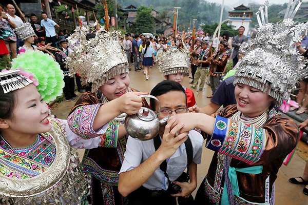 A tourist participates in a local Miao ethnic tradition in Liuzhou, Guangxi Zhuang autonomous region. (Tan Kaixing/for China Daily)