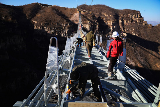 Work on the world's longest glass-floor bridge proceeds in the Hongyagu Scenic Area in Hebei province earlier this month. The bridge will open to the public on Dec 24. [Photo provided to China Daily]