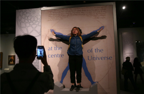 A visitor poses in front of a replica of Vitruvian Man by Leonardo da Vinci at Art, Culture and Daily Life in Renaissance Italy, an exhibition at the Capital Musuem in Beijing through June 22. (Photo by Zou Hong/China Daily)